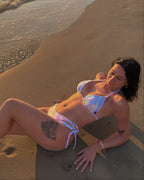 Woman in a bikini lying on the sand at the beach with waves in the background