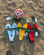 Colorful FIFA World cup teams country bikini sets on a sandy surface with a beach ball.